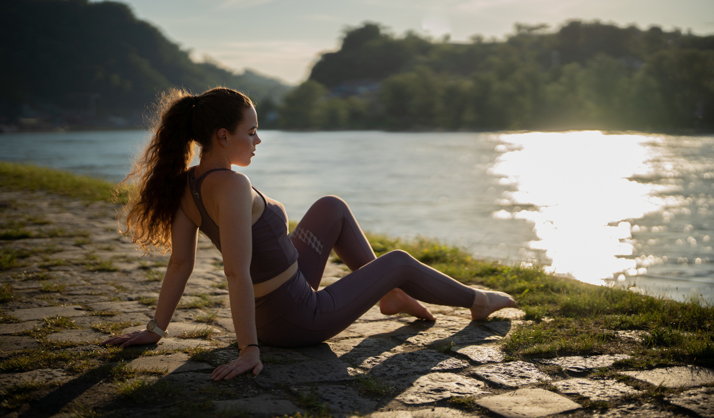 Спортивная девушка сидит на берегу реки