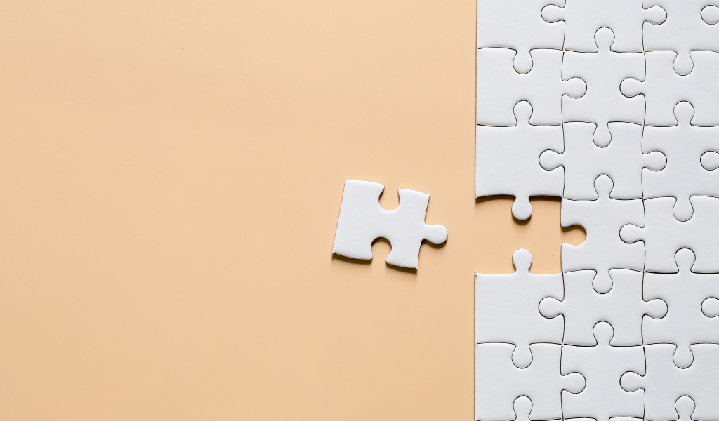 Белый пазл собирают на бежевом фоне