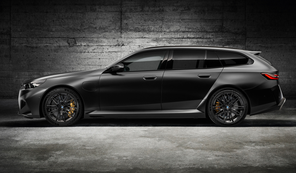 Вид сбоку на черный автомобиль BMW M5 Touring 2024 года