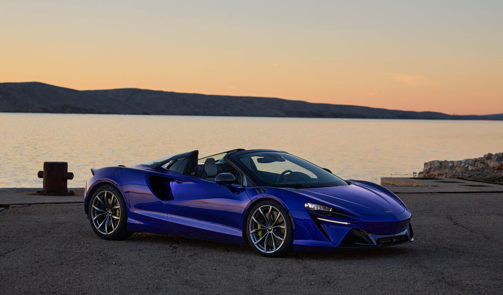 Синий быстрый автомобиль McLaren Artura Spider у воды