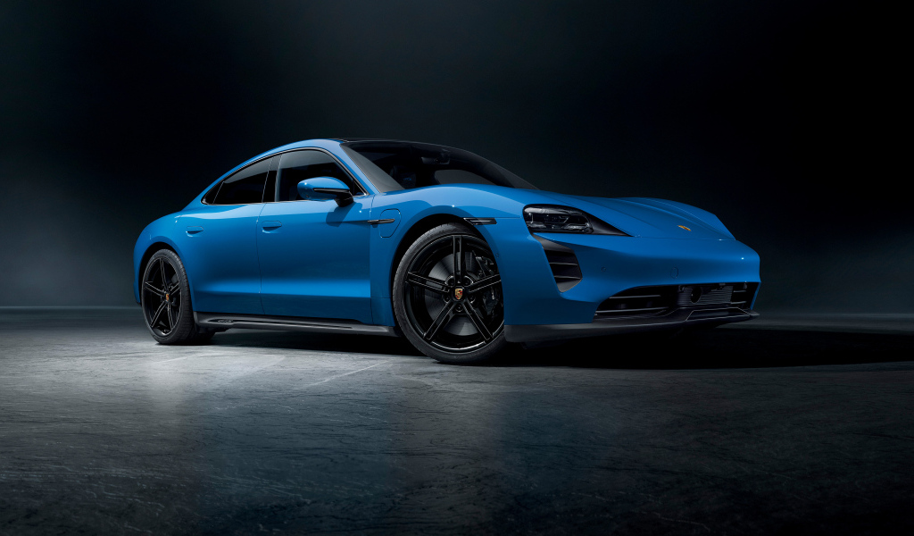 Синий автомобиль Porsche Taycan GTS на черном фоне