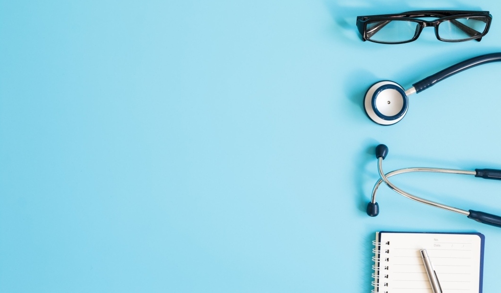 Стетоскоп, очки и блокнот на голубом фоне
