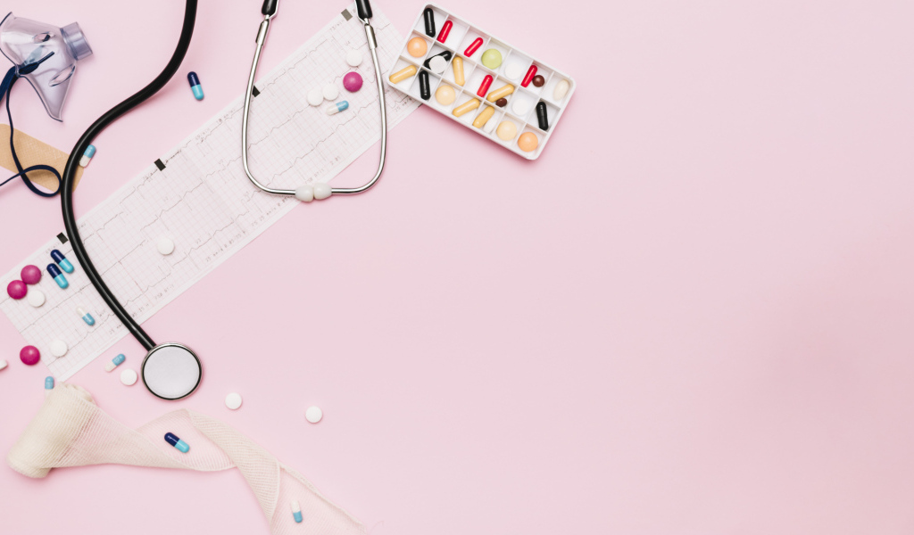 Стетоскоп и лекарства на кардиограмме на розовом фоне