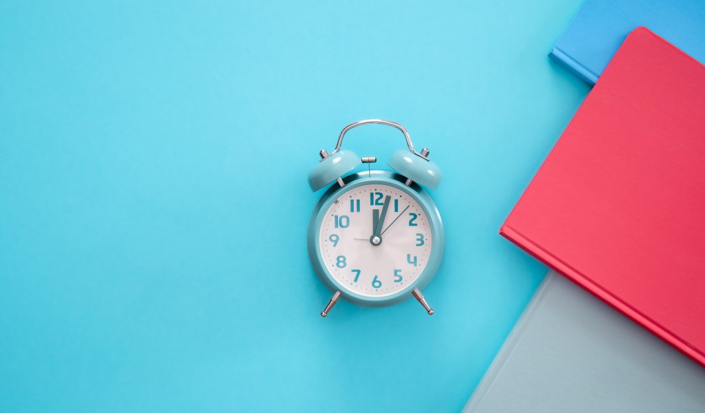 Будильник с книгами на голубом фоне