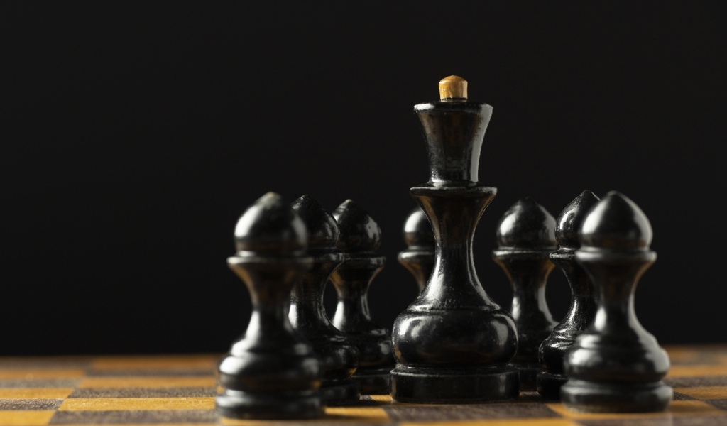 Черные шахматные фигуры на доске на черном фоне