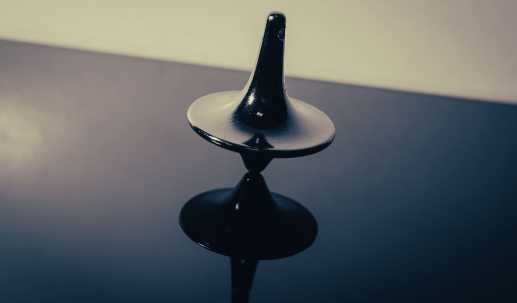 Черный волчок на ровной поверхности