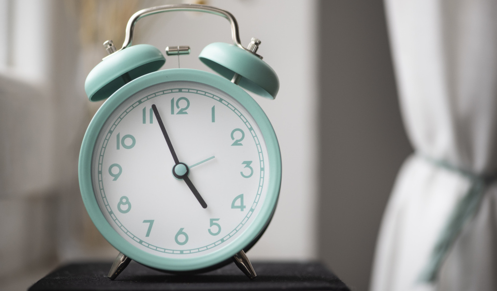 Голубой будильник стоит на книге в комнате