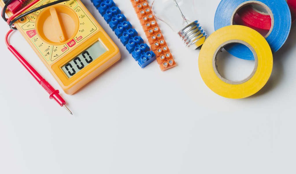 Электрическические приборы, мультиметр, изолента на сером фоне