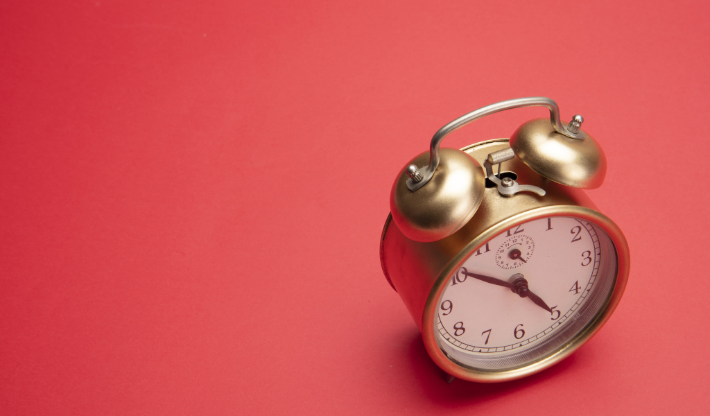 Золотой будильник на красном фоне