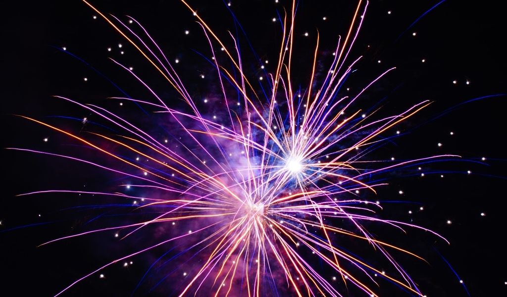 Разноцветные сиреневые искры фейерверка на черном фоне