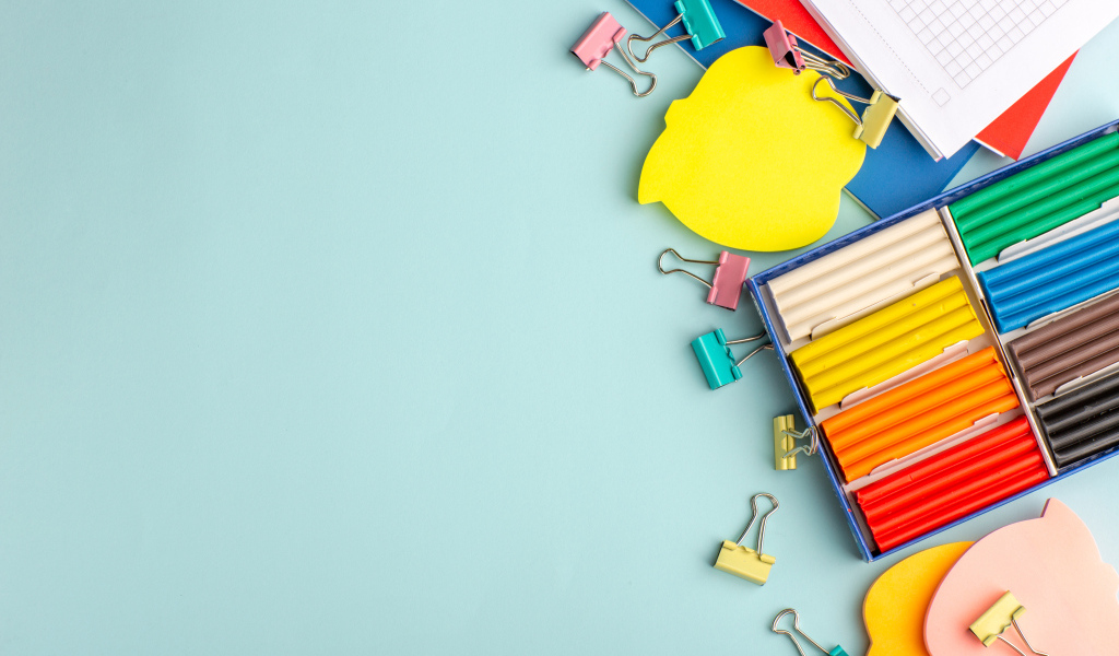 Пластилин на голубом фоне со скрепками и блокнотами