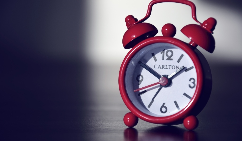 Красный будильник на черном столе