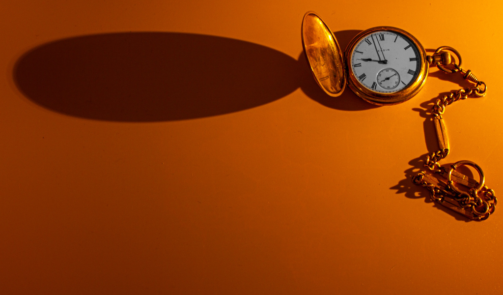 Тень от карманных часов на оранжевом фоне