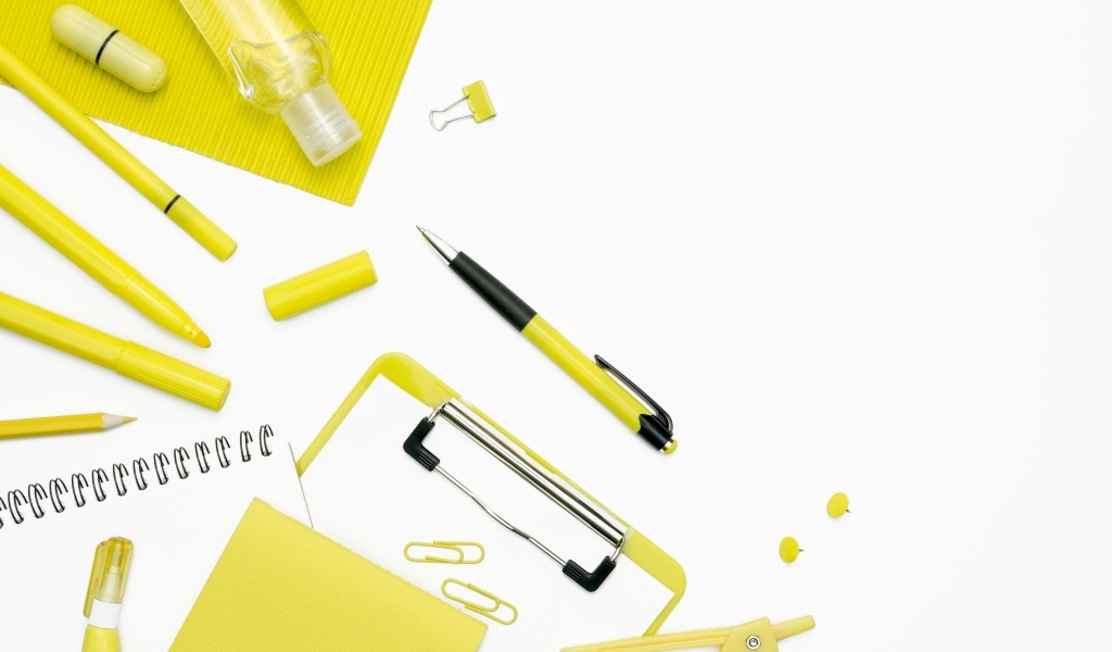 Желтые канцелярские предметы на белом фоне