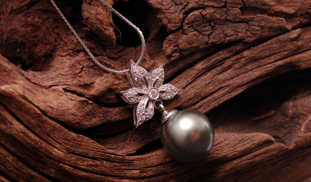 Кулон на цепочке лежит на старом дереве