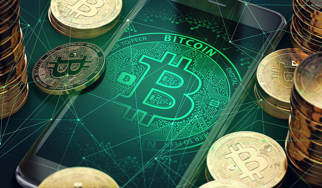 Золотые монеты биткоин со смартфоном на столе