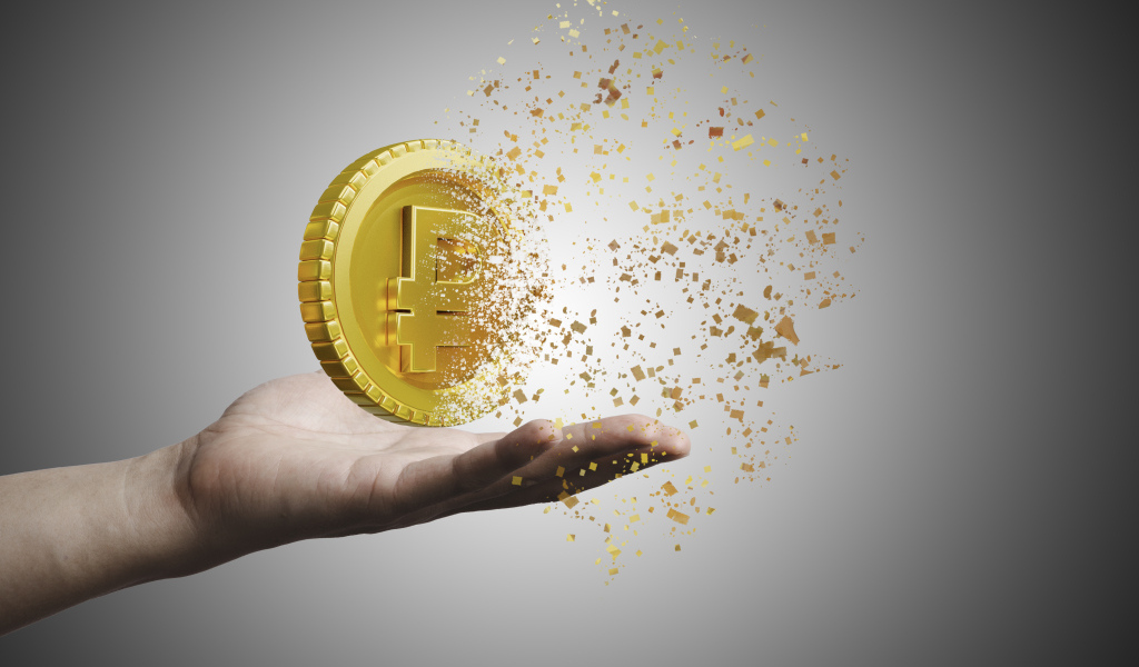 Монета разрушается на ладони на сером фоне