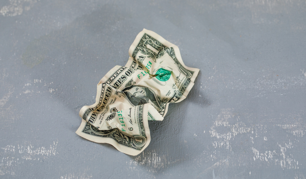 Смятая купюра один доллар на сером столе