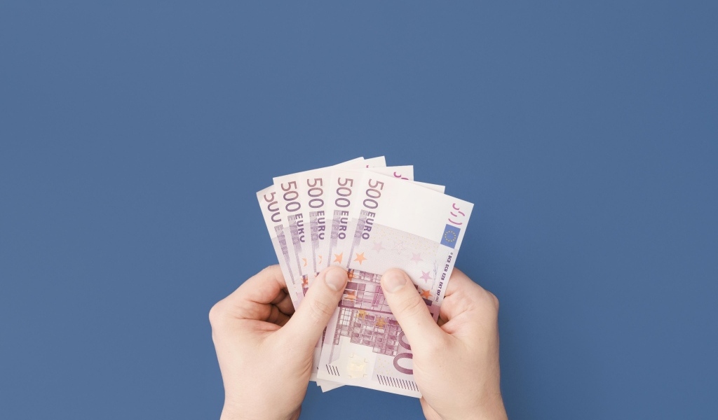 Купюры в пятьсот евро в руках на синем фоне