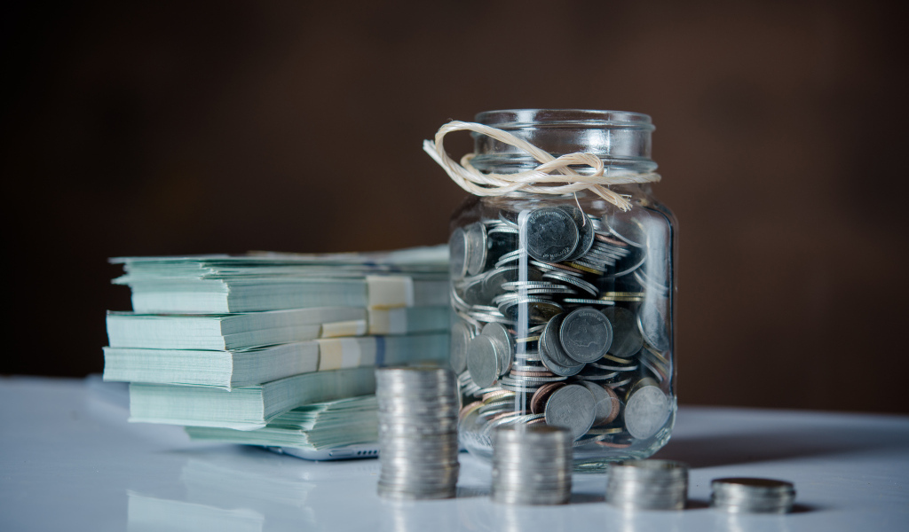 Банка с монетами на столе с пачками денег