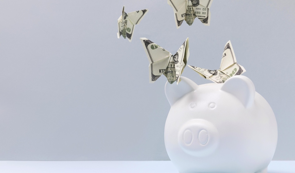 Свинья копилка с бабочками из купюр на сером фоне