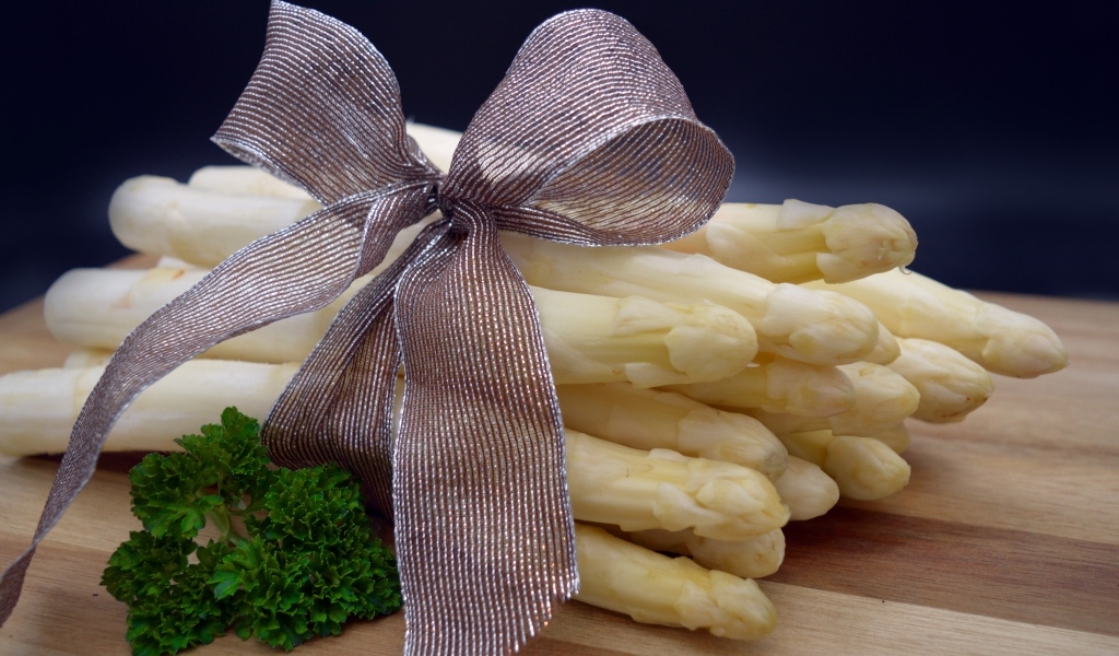 Спаржа с бантом на столе с петрушкой