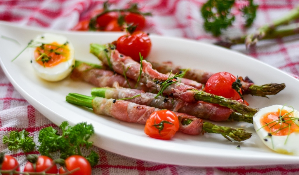 Спаржа в беконе на тарелке с вареными яйцами