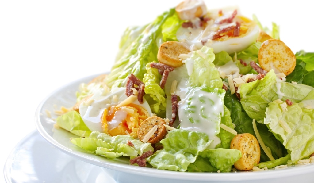 Салат Цезарь на большой белой тарелке