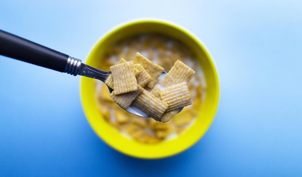 Хлопья с молоком на ложке на голубом фоне