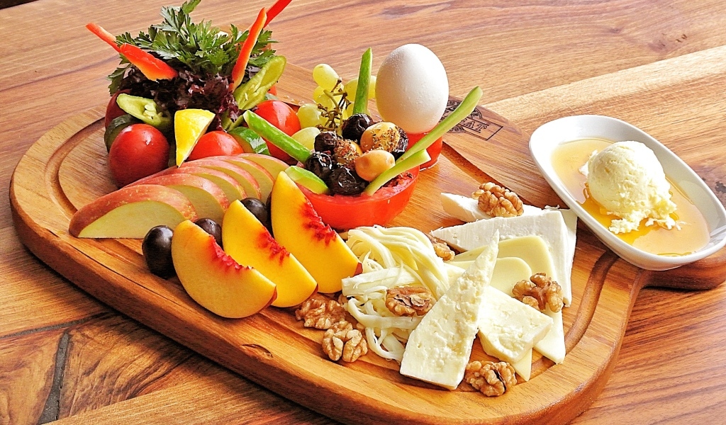 Сыр на доске с фруктами и салатом