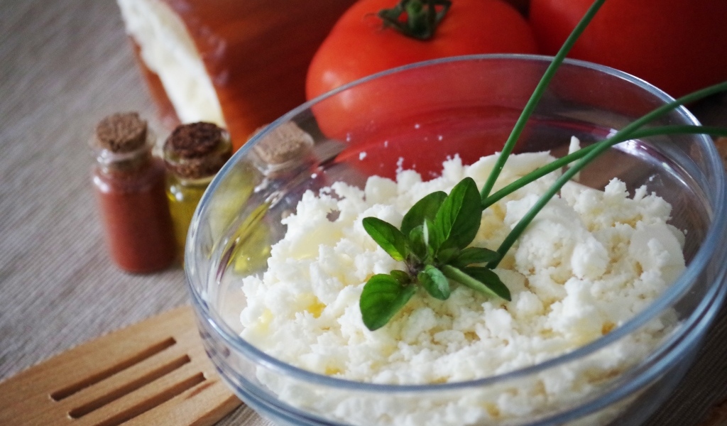 Творог в тарелке на столе с помидорами