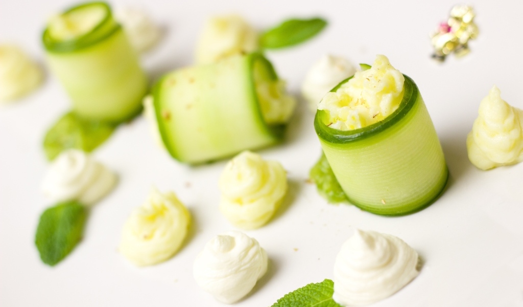 Рулетики из огурца с кремом на белом фоне