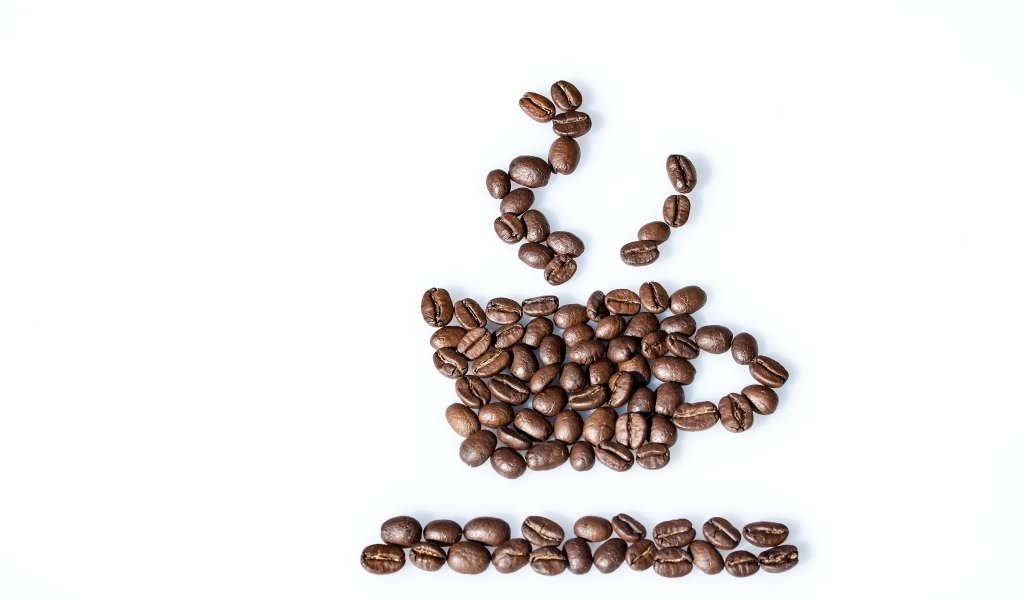 Чашка из кофейных зерен на белом столе
