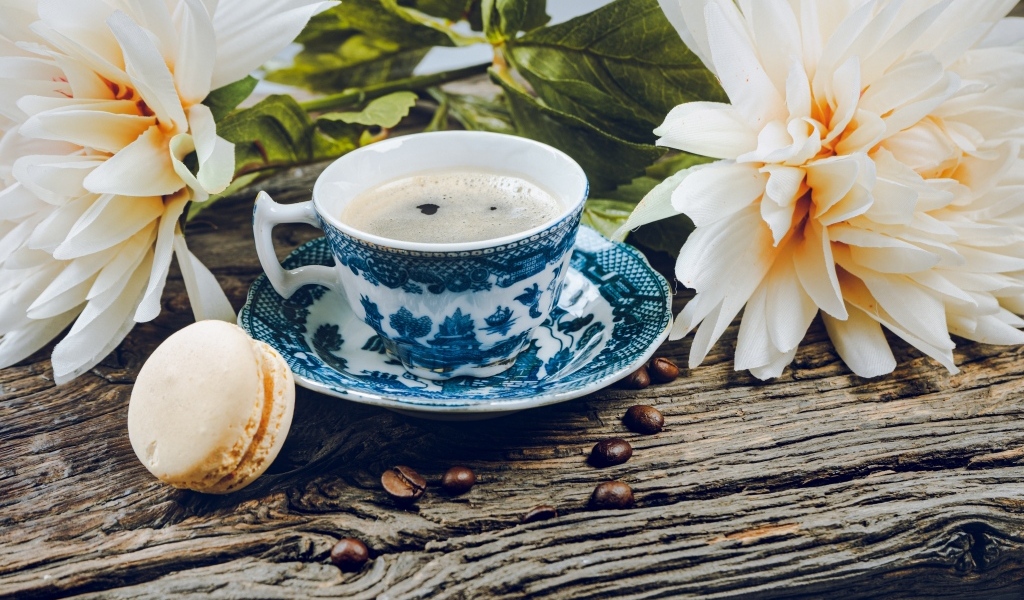 Чашка кофе с макарунами на столе с цветами