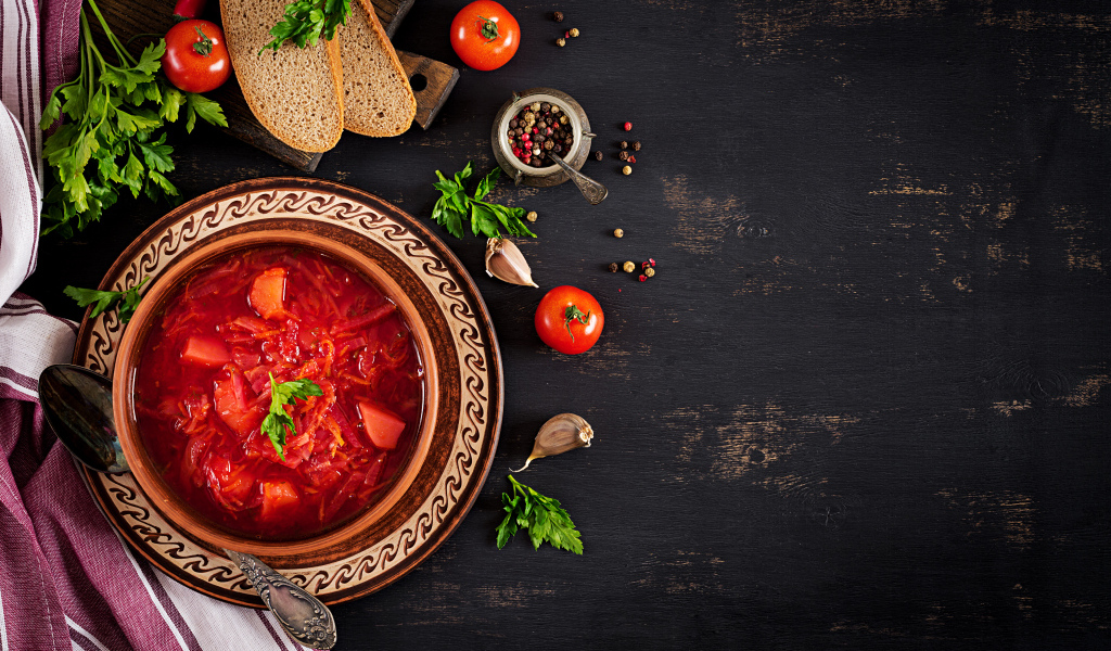 Вкусный красный борщ в тарелке на столе