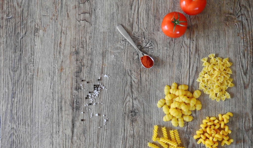 Разные виды макарон на столе с помидорами