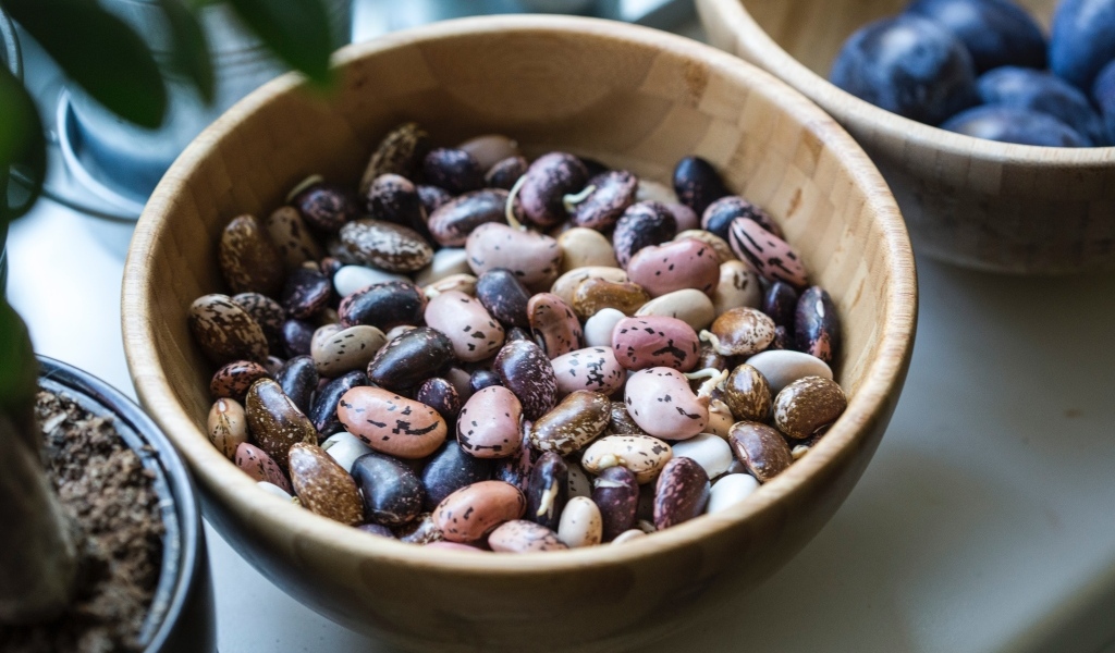Разноцветная фасоль в деревянной миске на столе