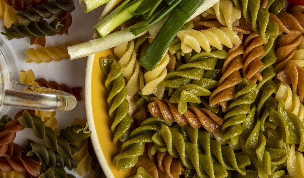 Разноцветные сваренные макароны с зеленым луком