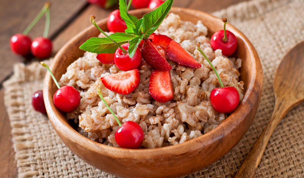 Овсяная каша с ягодами в деревянной миске