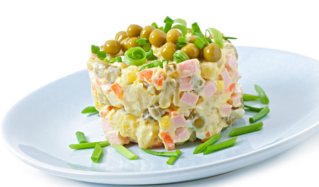 Салат оливье с зеленым горошком на тарелке 