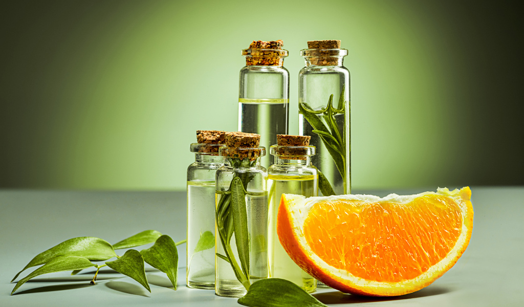 Апельсиновое масло на зеленом фоне с апельсинами