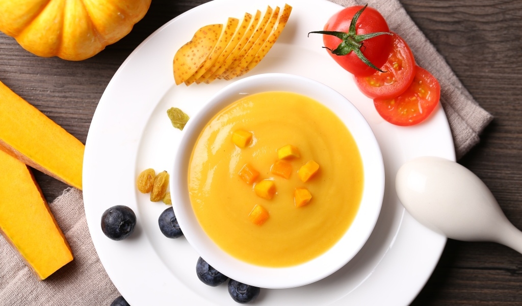 Тыквенный суп пюре на тарелке с картофелем и помидором