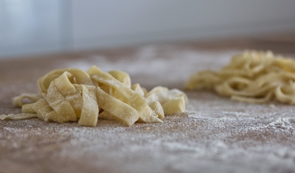 Сырое тесто для лапши на покрытом мукой столе