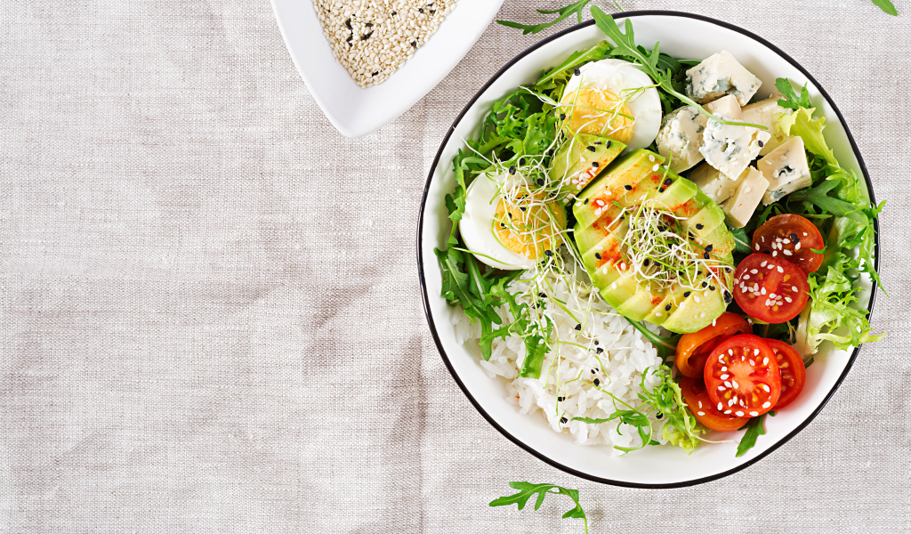 Рис с овощами и авокадо в тарелке