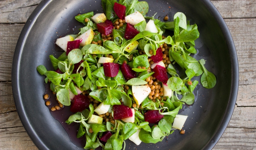 Салат с зеленью в большой черной тарелке