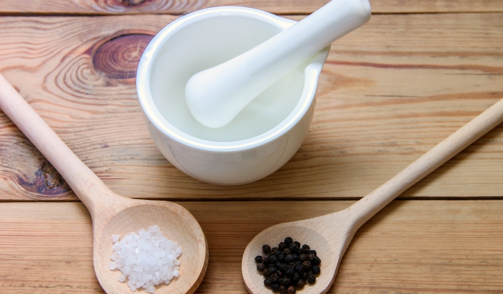 Соль с перцем на столе с деревянной ступкой