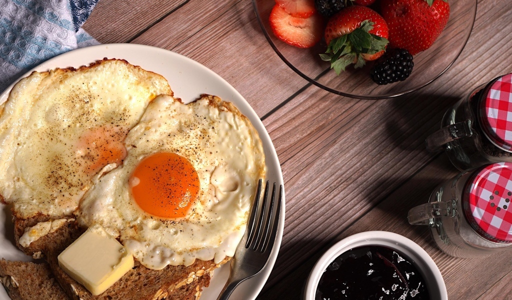 Яичница с гренками на столе с клубникой