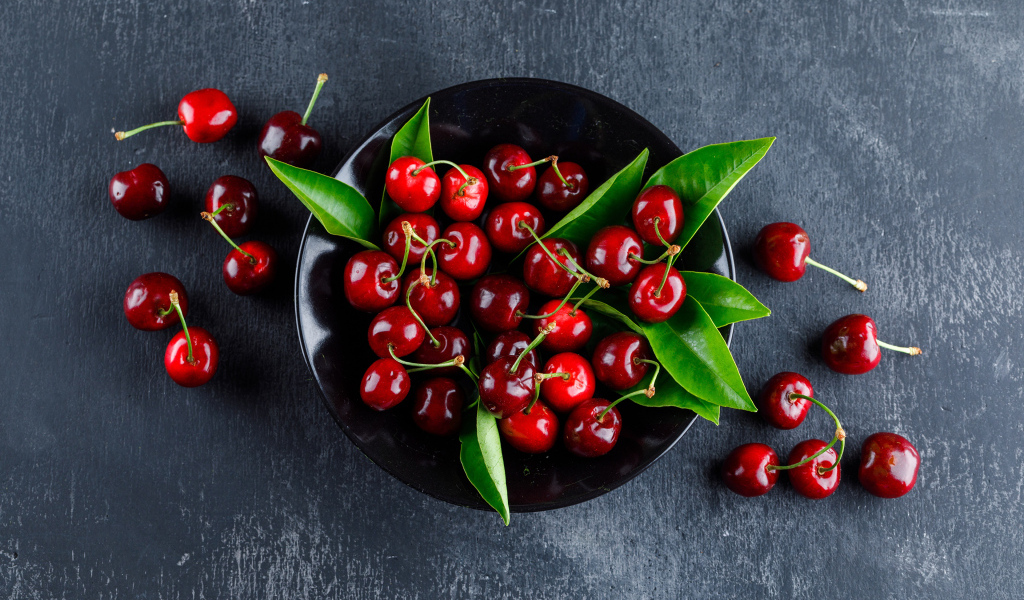 Черная  тарелка с красными ягодами черешни