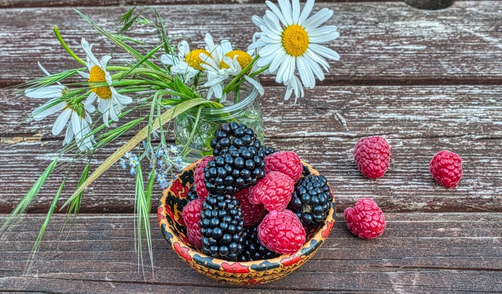 Ягоды черники и малины на столе с ромашками