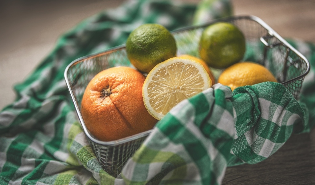 Цитрусовые фрукты в железной корзинке на столе